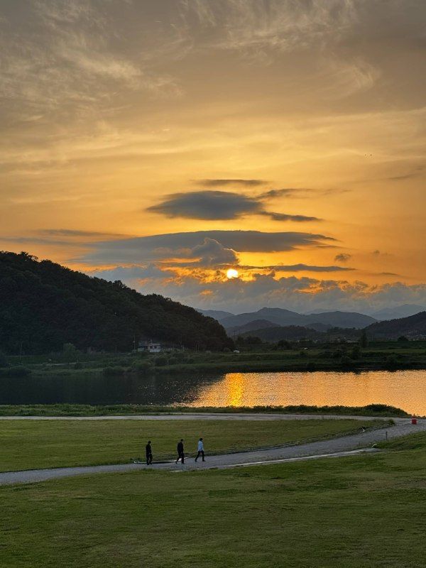Golden sunset over a river valley, three small walkers on a riverside path