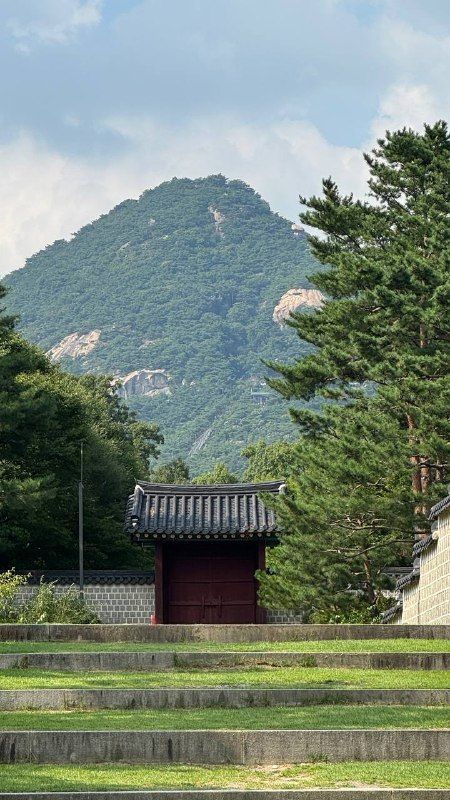 Palace roofs and a stone terrace beneath a rocky mountain