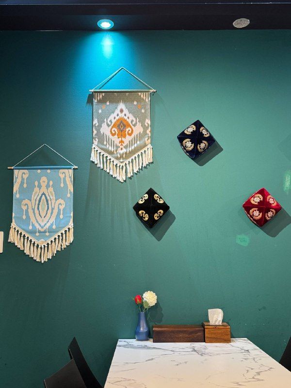 Teal restaurant wall hung with embroidered tapestries