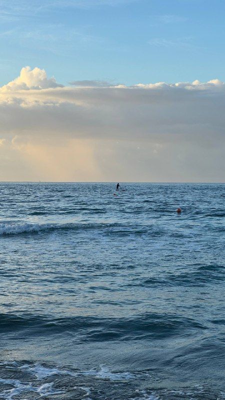 Open sea and low waves under a bright, hazy sky