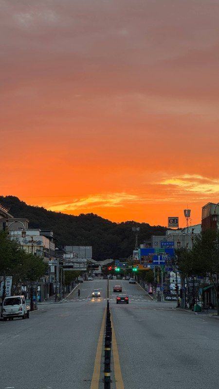 The town's main road at sunset, the sky burning orange over the hills