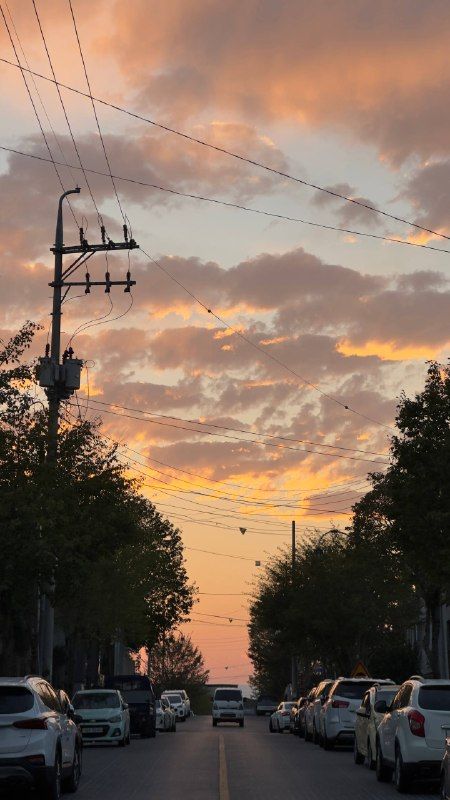A residential street at dusk under golden clouds and power lines
