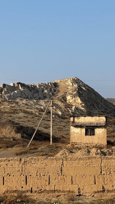 An adobe house in front of an eroded clay hill
