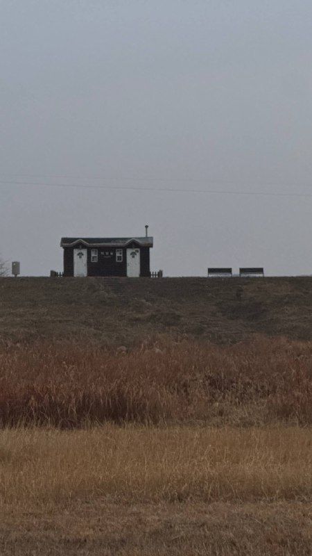 A dry brown field running to a distant watchtower