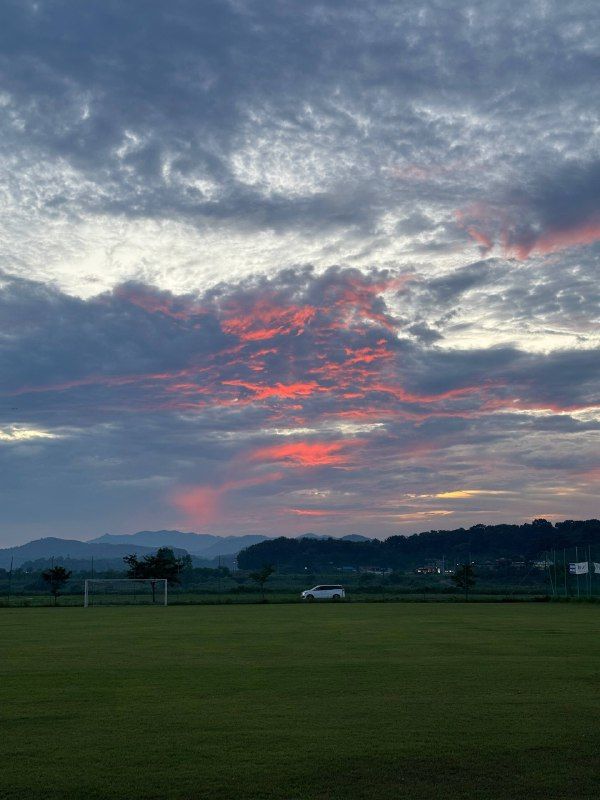 Pink-lit evening clouds above dark green fields