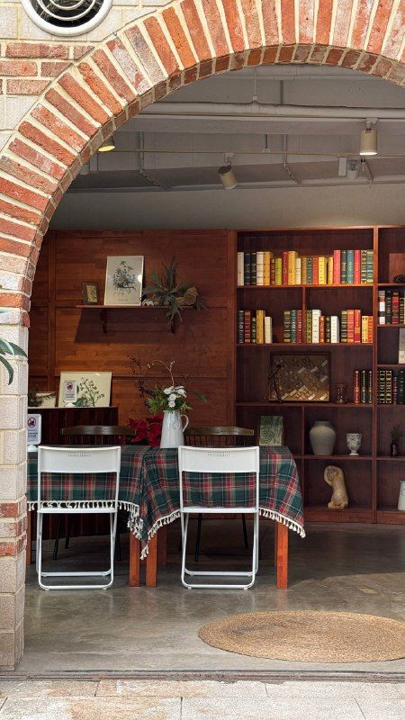 A café under a brick arch with bookshelves and checked tablecloths